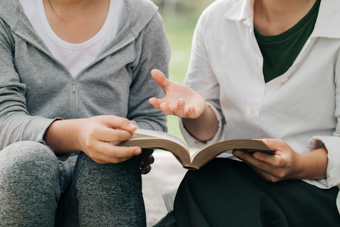 Two women studying and  talking about the bible .